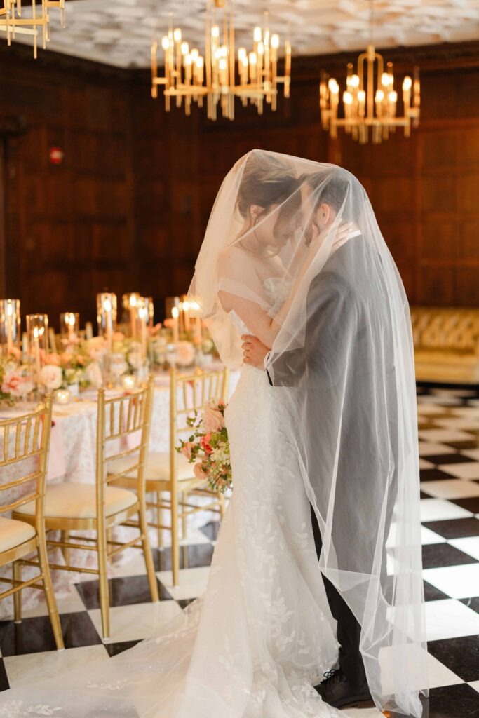 A bride and groom inside the bride's veil next to a reception table at their Blackstone Hotel Chicago wedding